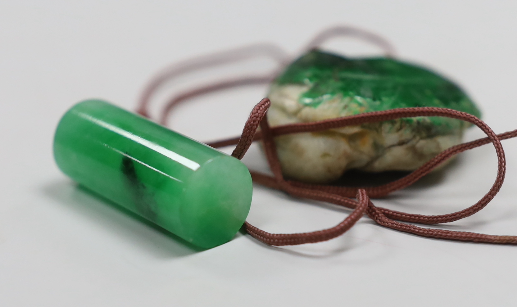 Two jadeite pendants and a handle tip